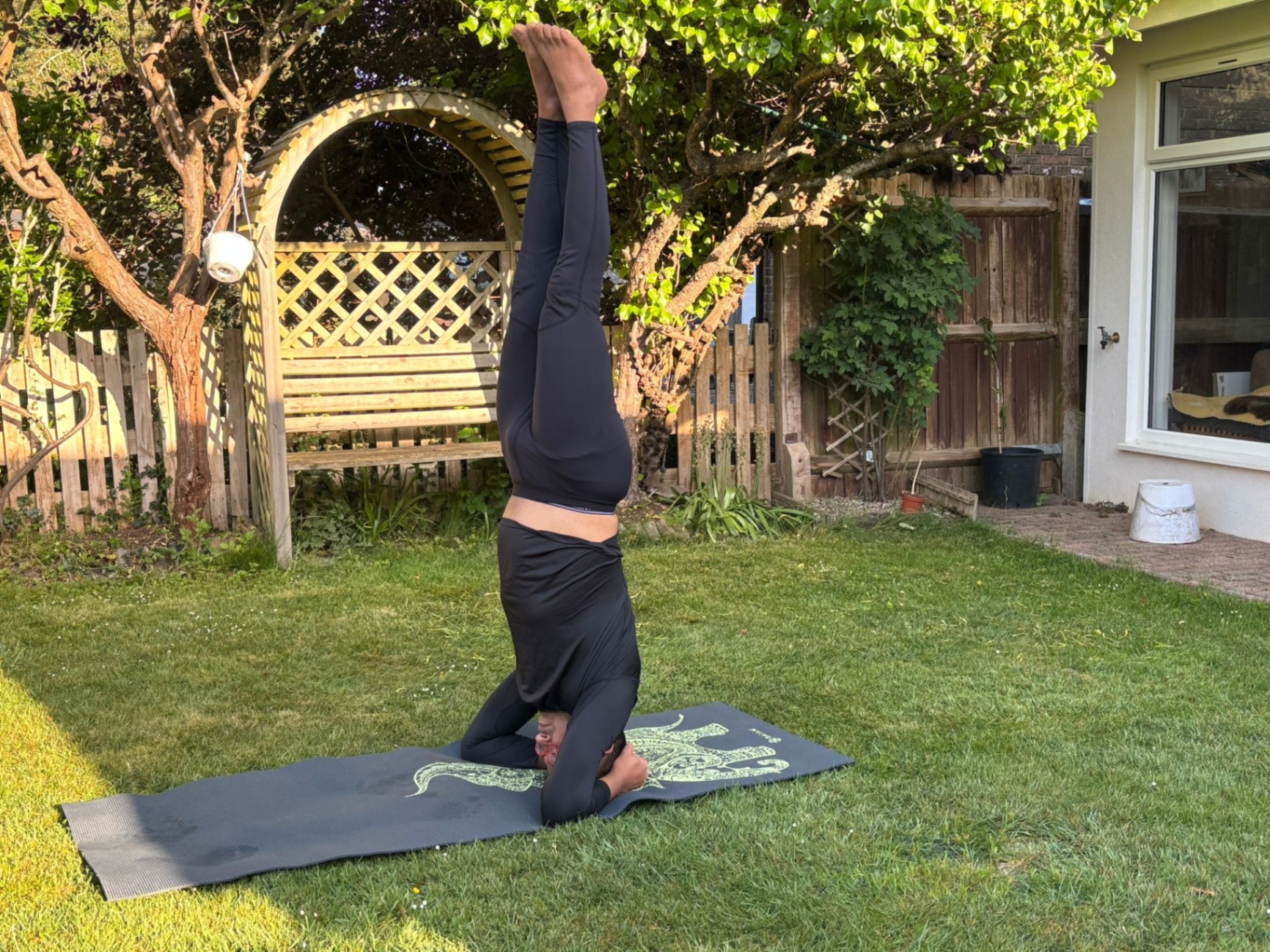 Yoga practitioner performing a headstand in a peaceful garden setting